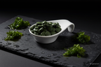 Chlorella Tabletten in weißer Keramikschale auf Schieferplatte, KI-generiert