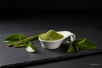 Matcha Pulver in weißer Keramikschale auf Schieferplatte, KI-generiert