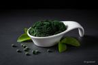 Spirulina Pulver in weißer Keramikschale auf Schieferplatte, KI-generiert